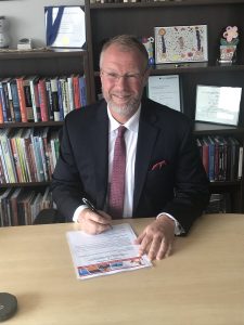 President Tim Loreman signs the statement of adoption of the Okanagan Charter