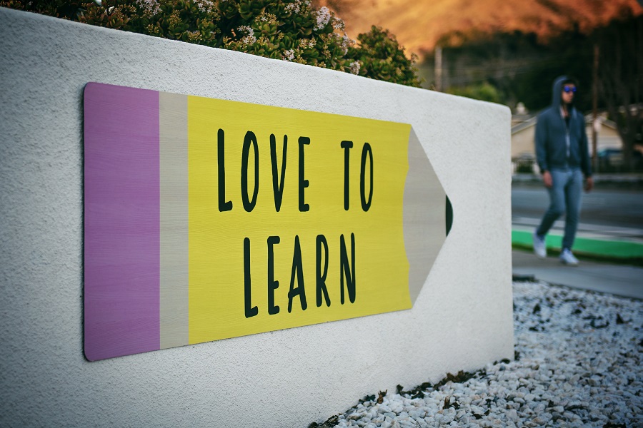 An image of a school sign with the text "love to learn." In the background of the image someone walks by.